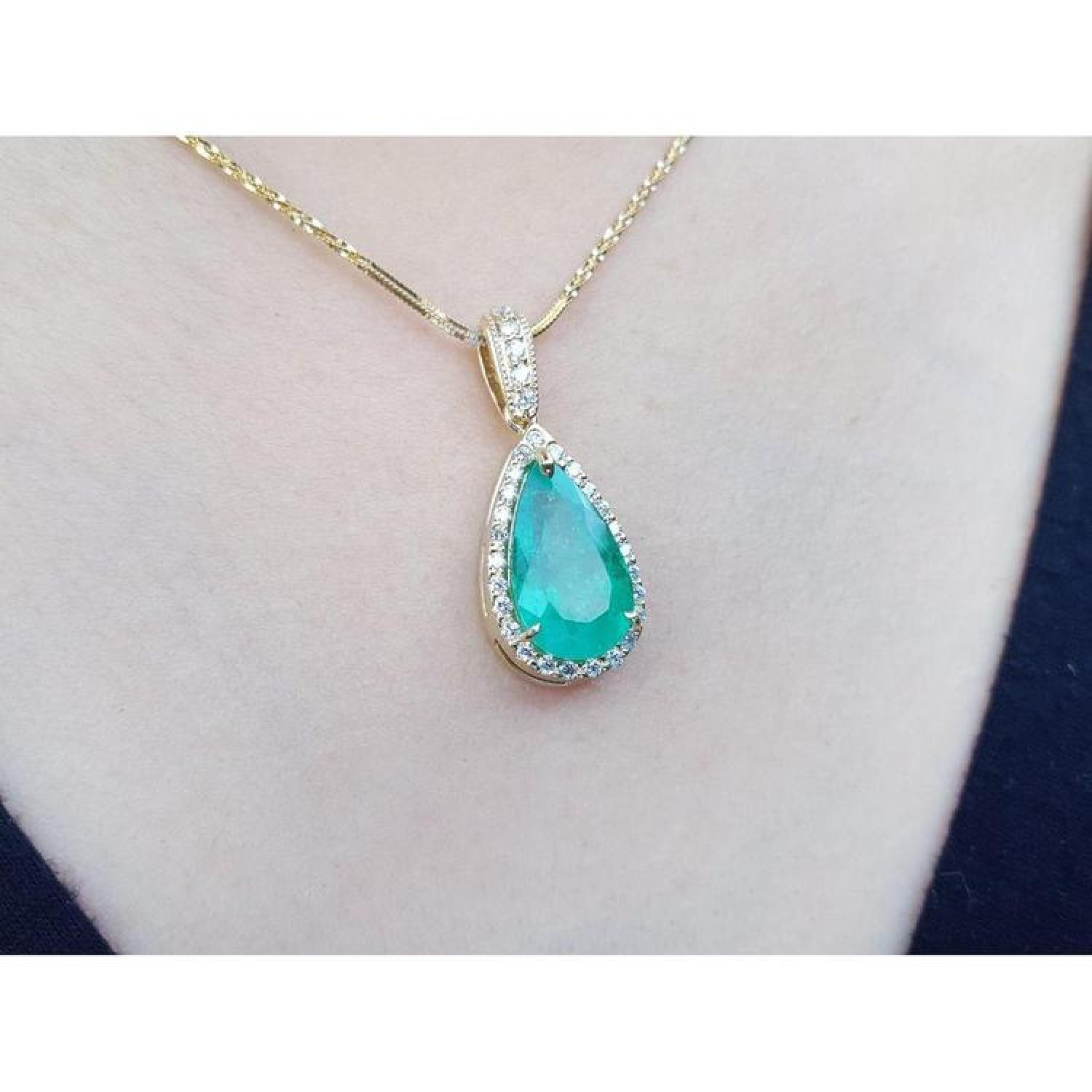 18K yellow gold teardrop emerald pendant with halo diamonds on a delicate chain.