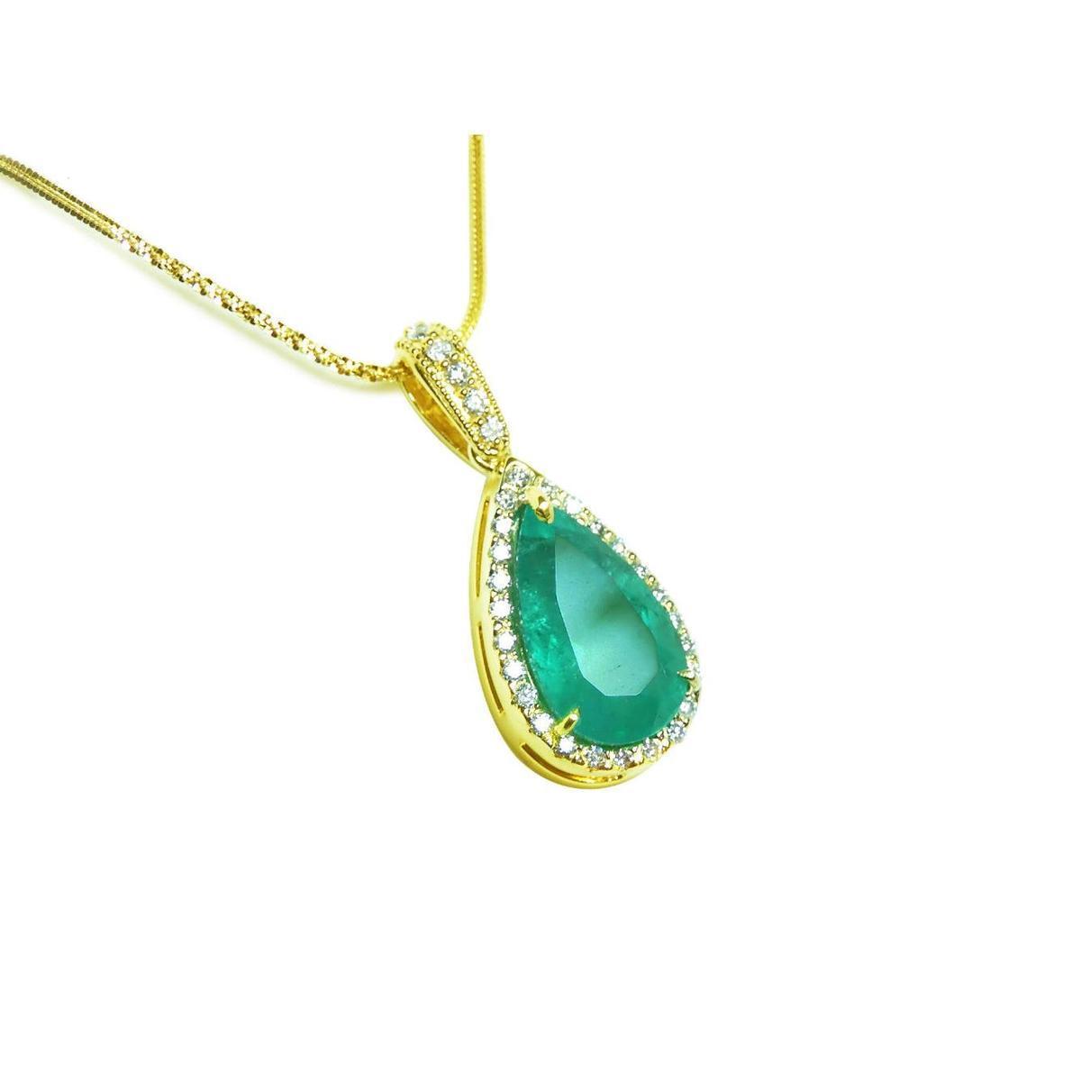 Gold necklace with a natural emerald teardrop pendant topside view on a white background