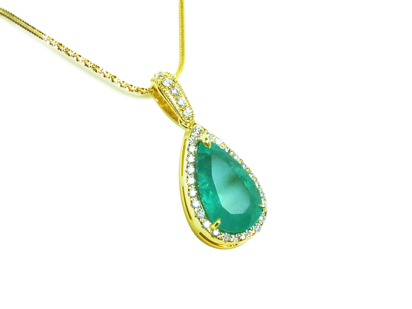 Gold necklace with a natural emerald teardrop pendant topside view on a white background