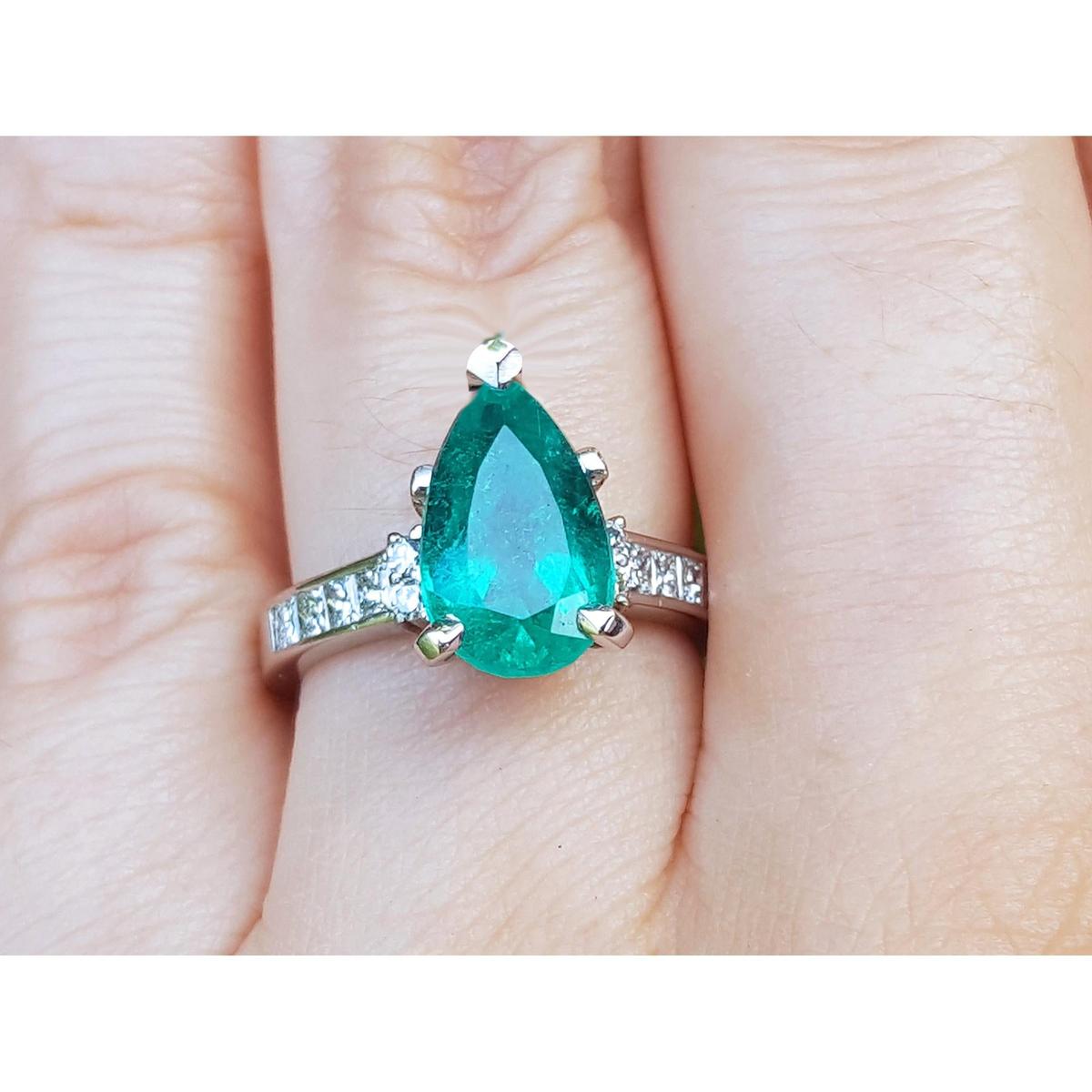 A Colombian emerald teardrop natural gemstone ring on a hand.