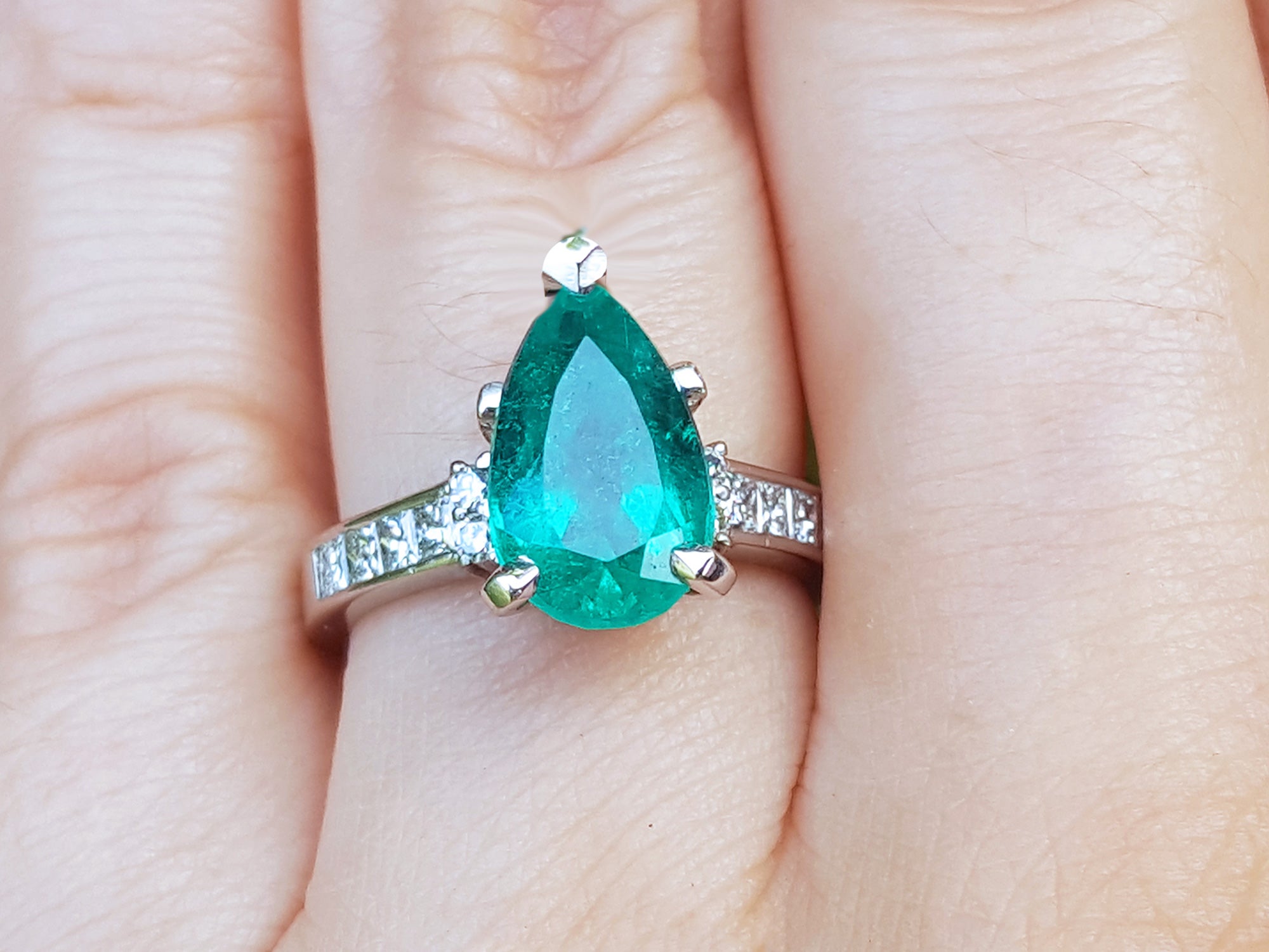 A Colombian emerald teardrop natural gemstone ring on a hand.