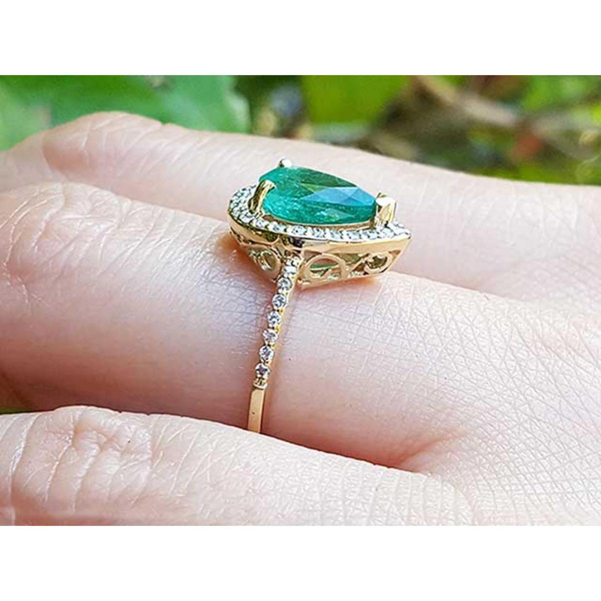 The topside and underside view of a teardrop emerald ring on a person's finger.