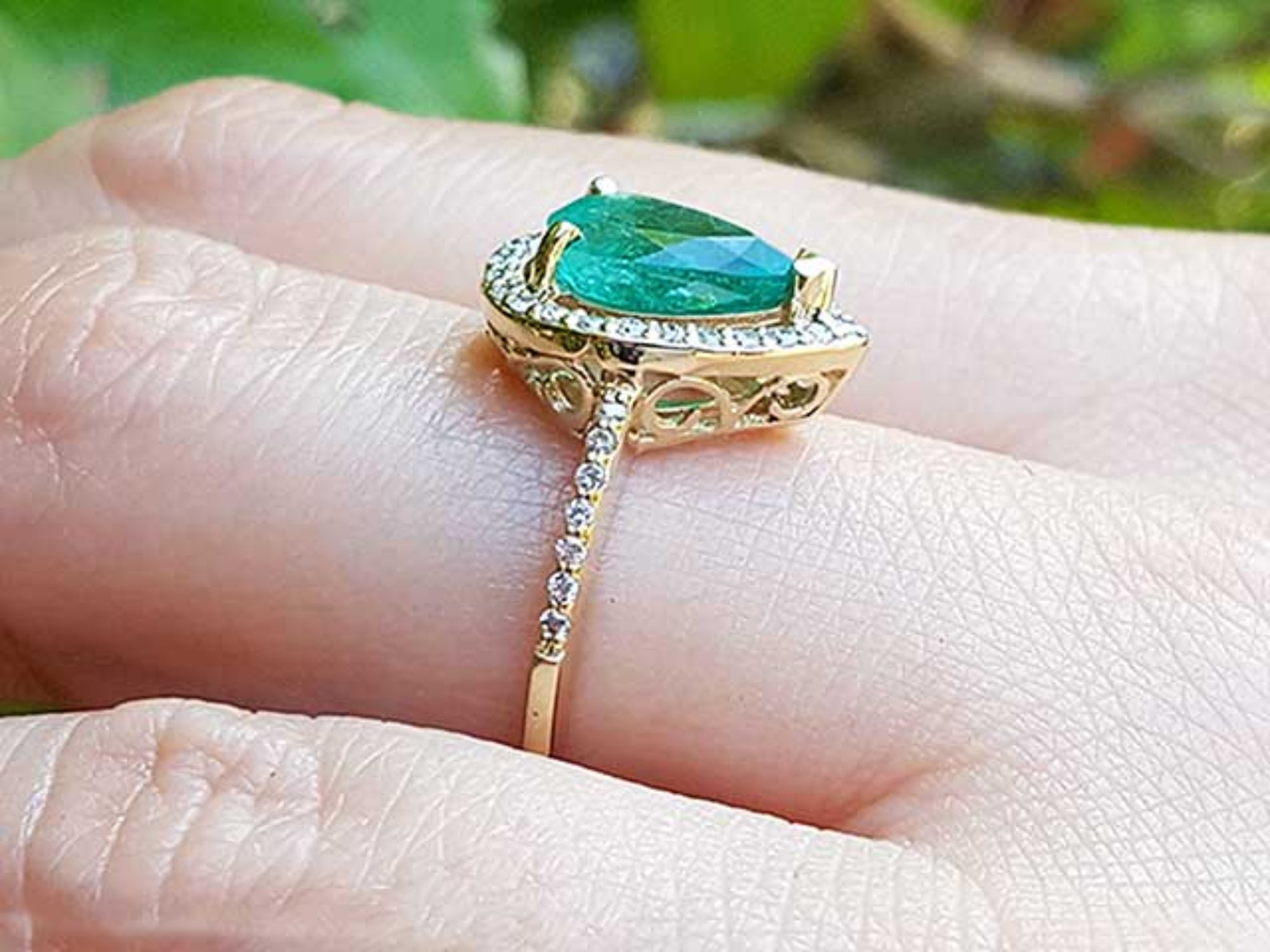 The topside and underside view of a teardrop emerald ring on a person&#39;s finger.