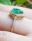 The topside and underside view of a teardrop emerald ring on a person's finger.