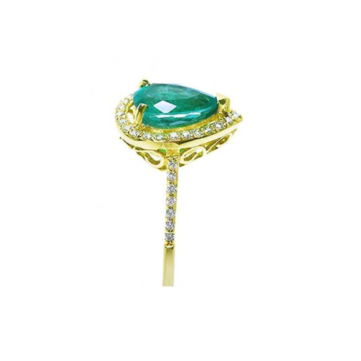 Side profile of a pear cut emerald with diamonds around, gallery and band ring in yellow gold.