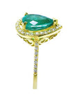 Side profile of a pear cut emerald with diamonds around, gallery and band ring in yellow gold.