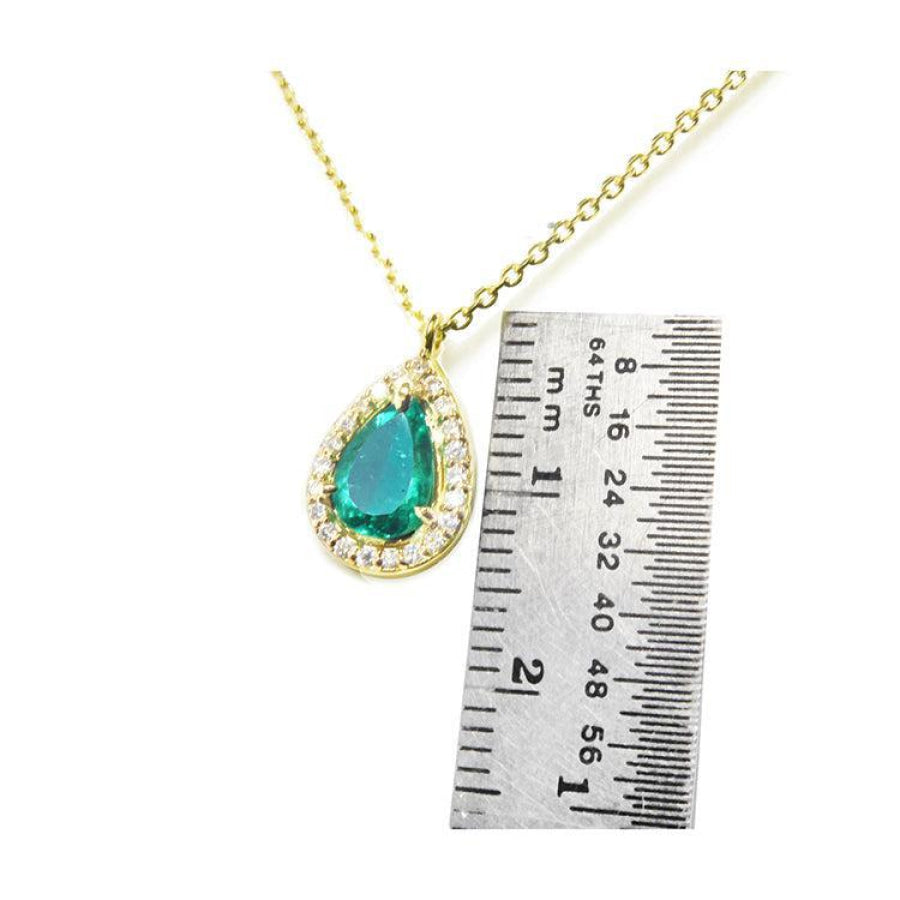 Pear-shaped natural emerald necklace with diamond halo in 14K yellow gold, shown next to a ruler.