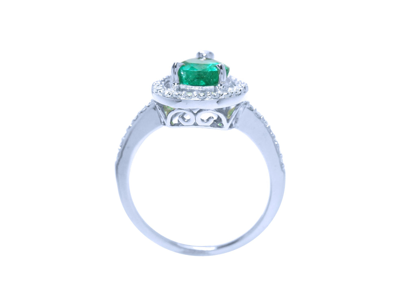 The lateral view of a natural emerald ring in white gold, top setting, gallery and band design visibles.