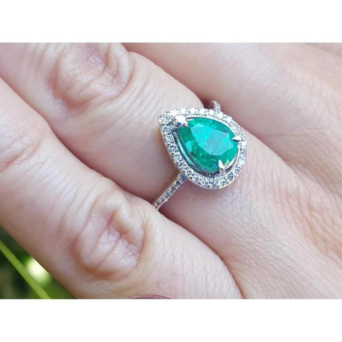 1.39 ct. teardrop emerald ring with diamond halo on a 14K white gold band.
