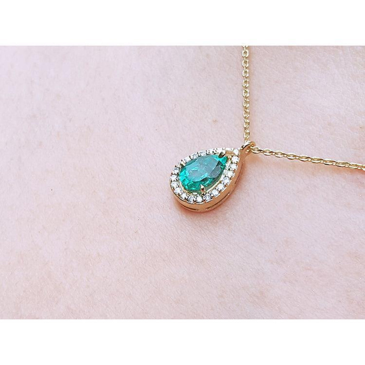Pear-shaped natural emerald necklace with diamond halo on 14K yellow gold chain.