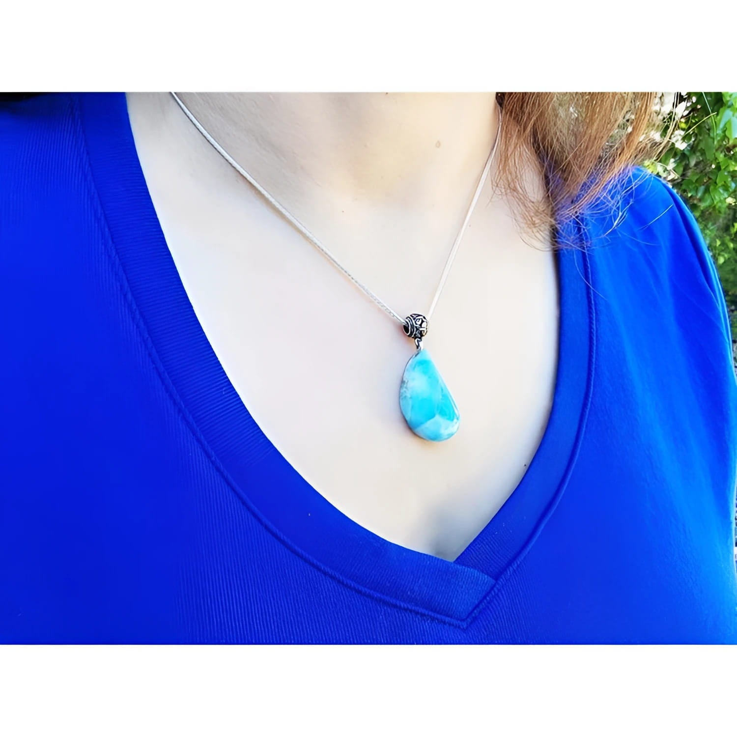 Larimar teardrop pendant on a sterling silver necklace, worn on a blue shirt.