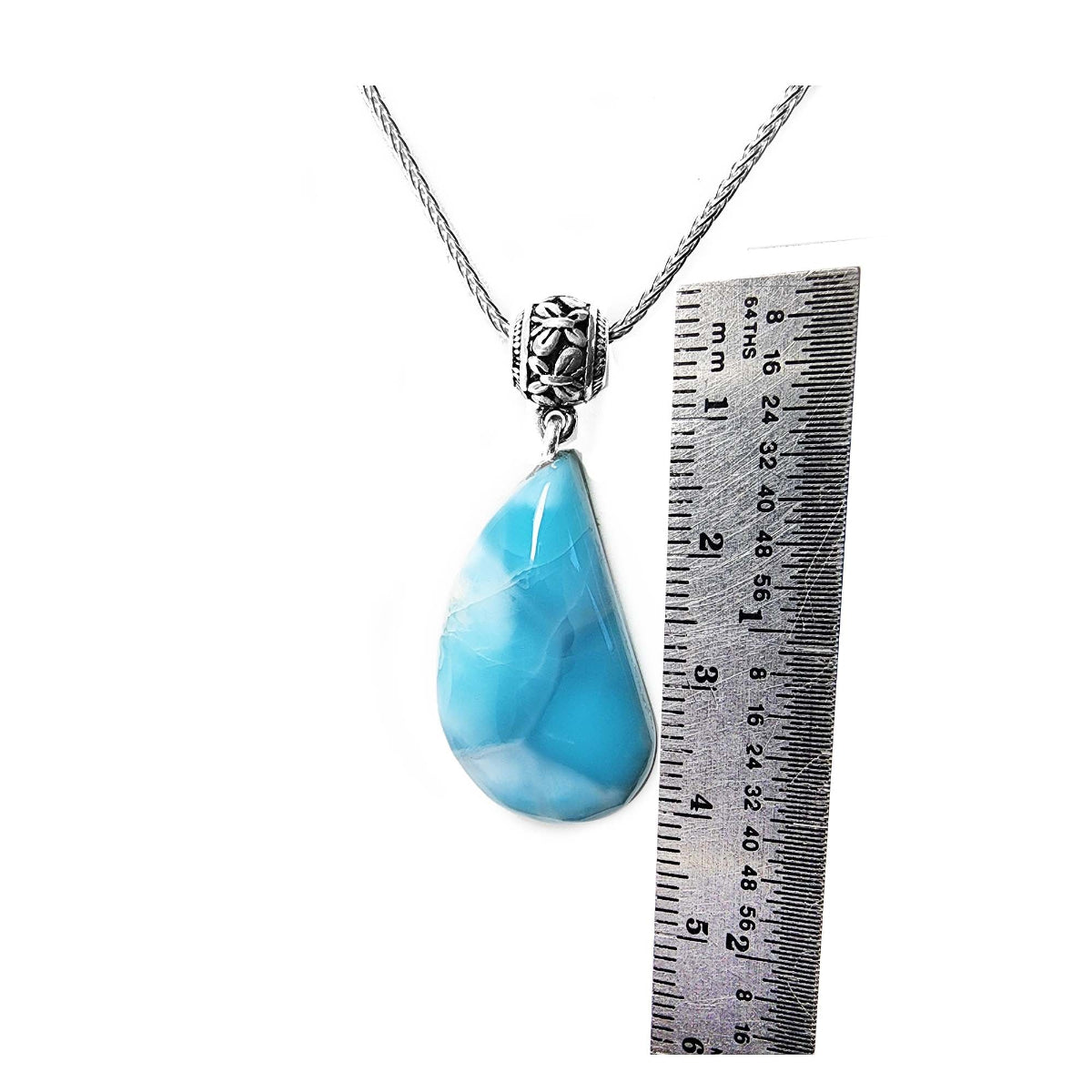 Teardrop-shaped blue larimar pendant on a chain with a ruler for scale on a white background