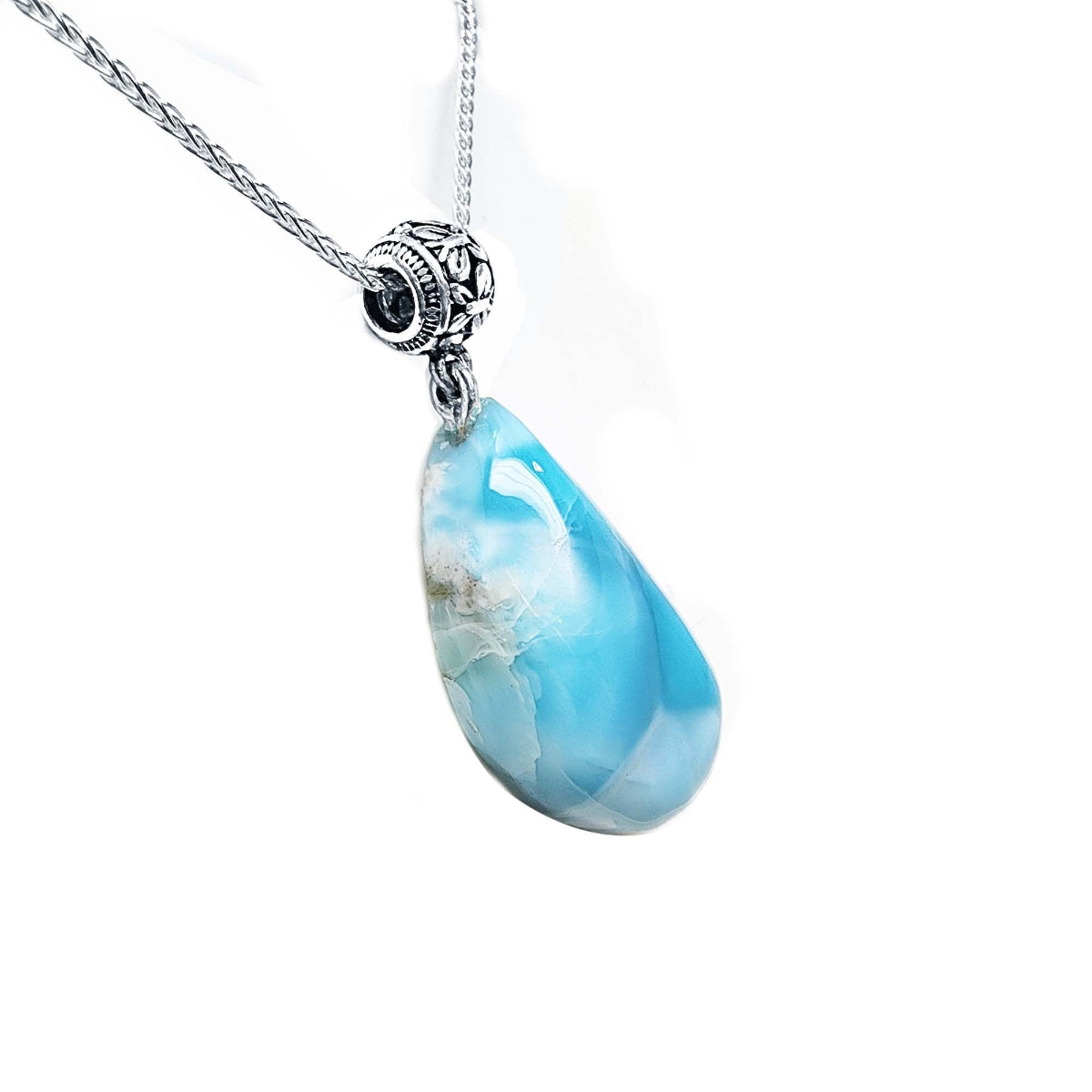 Teardrop-shaped blue larimar pendant on a silver chain on a right-side position view.