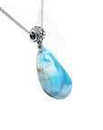 Teardrop-shaped blue larimar pendant on a silver chain on a right-side position view.