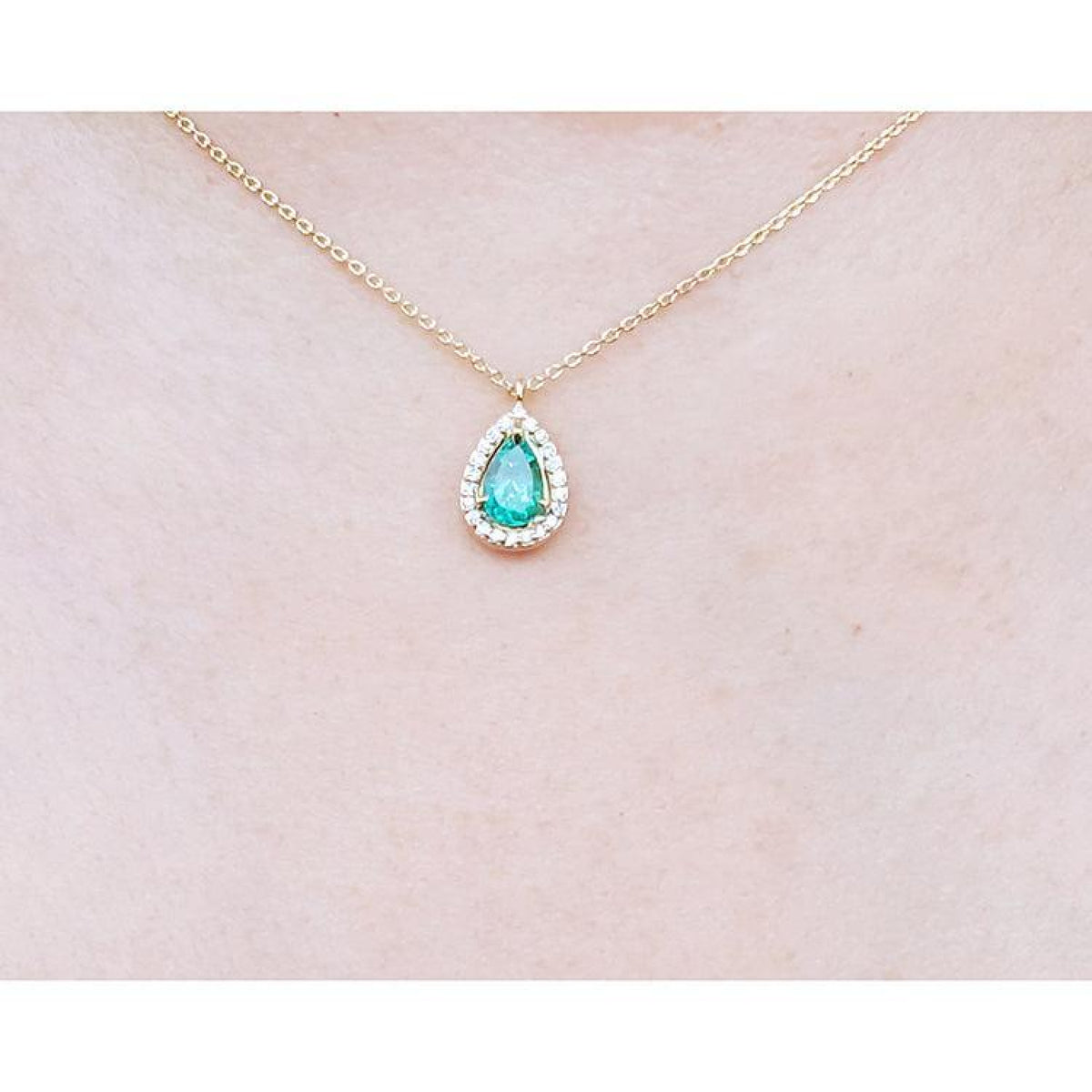 Pear-shaped natural emerald necklace with diamond halo on a 14K yellow gold chain.