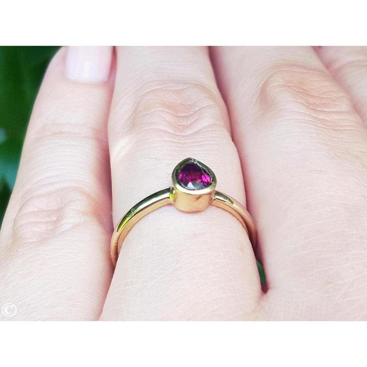 Woman's hand wearing a 14K yellow gold ring with a bezel-set teardrop natural ruby solitaire.