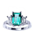 An emerald three stone ring side baguette diamonds, displaying a topside profile view. 