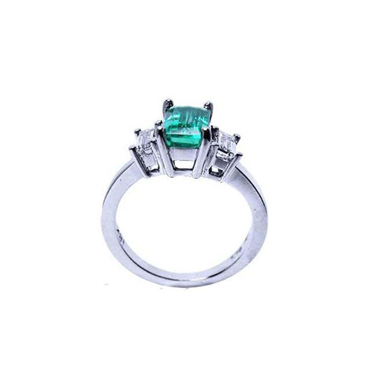 Emerald cut three stone ring with medium bluish green emerald and side baguette diamonds in 18K white gold.