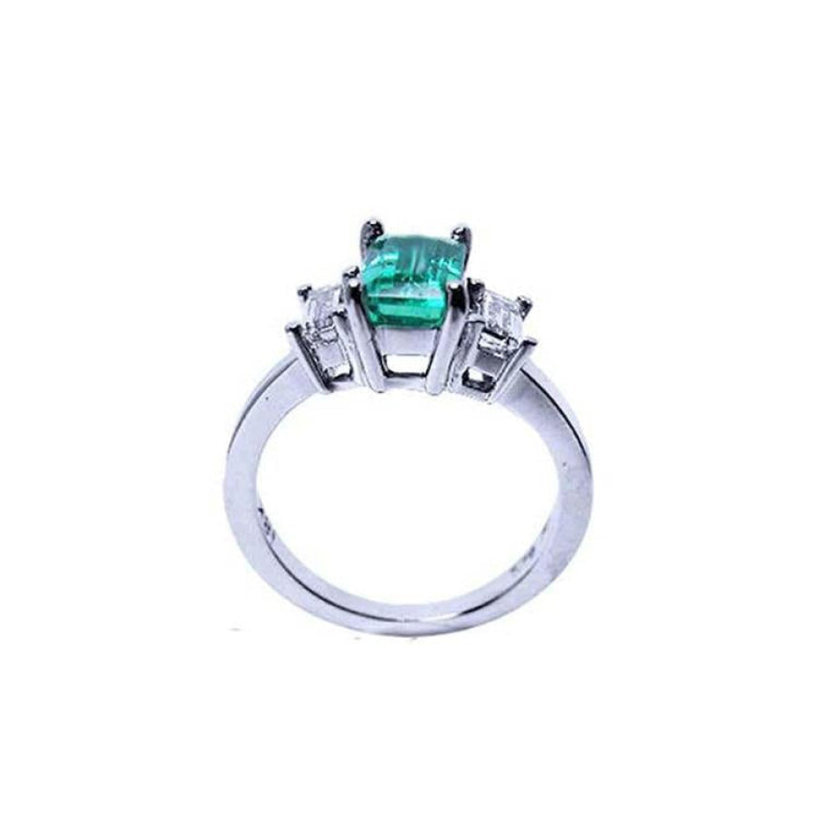 Emerald cut three stone ring with medium bluish green emerald and side baguette diamonds in 18K white gold.