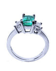 Lateral profile top and gallery view of a natural emerald three stone ring and two diamonds on a white background.