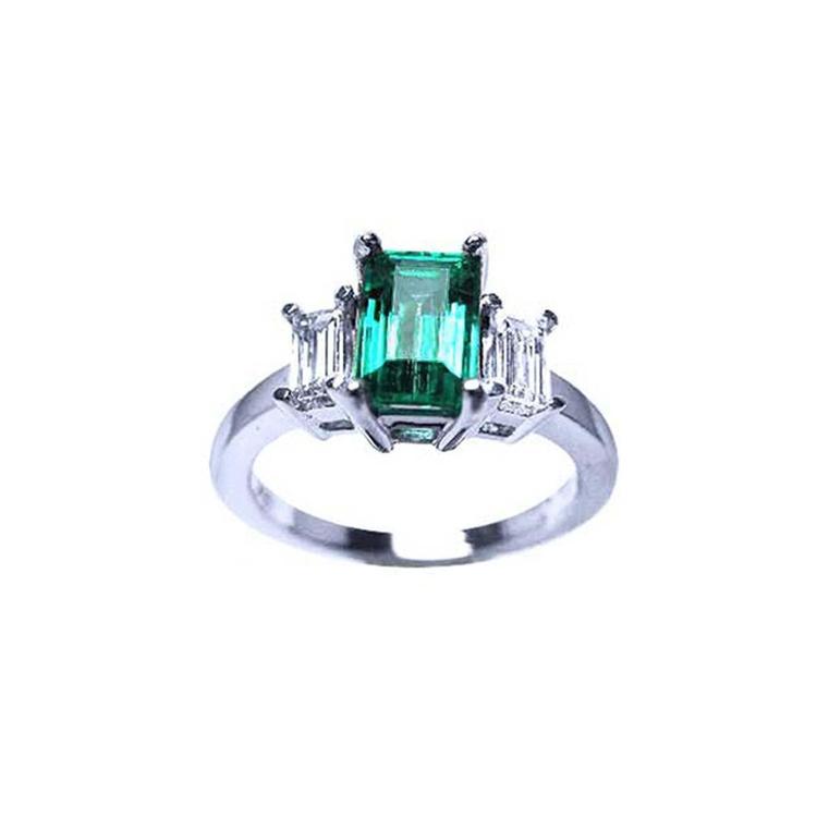 A women's emerald three stone ring in white gold, with a top profile view displaying side diamonds.