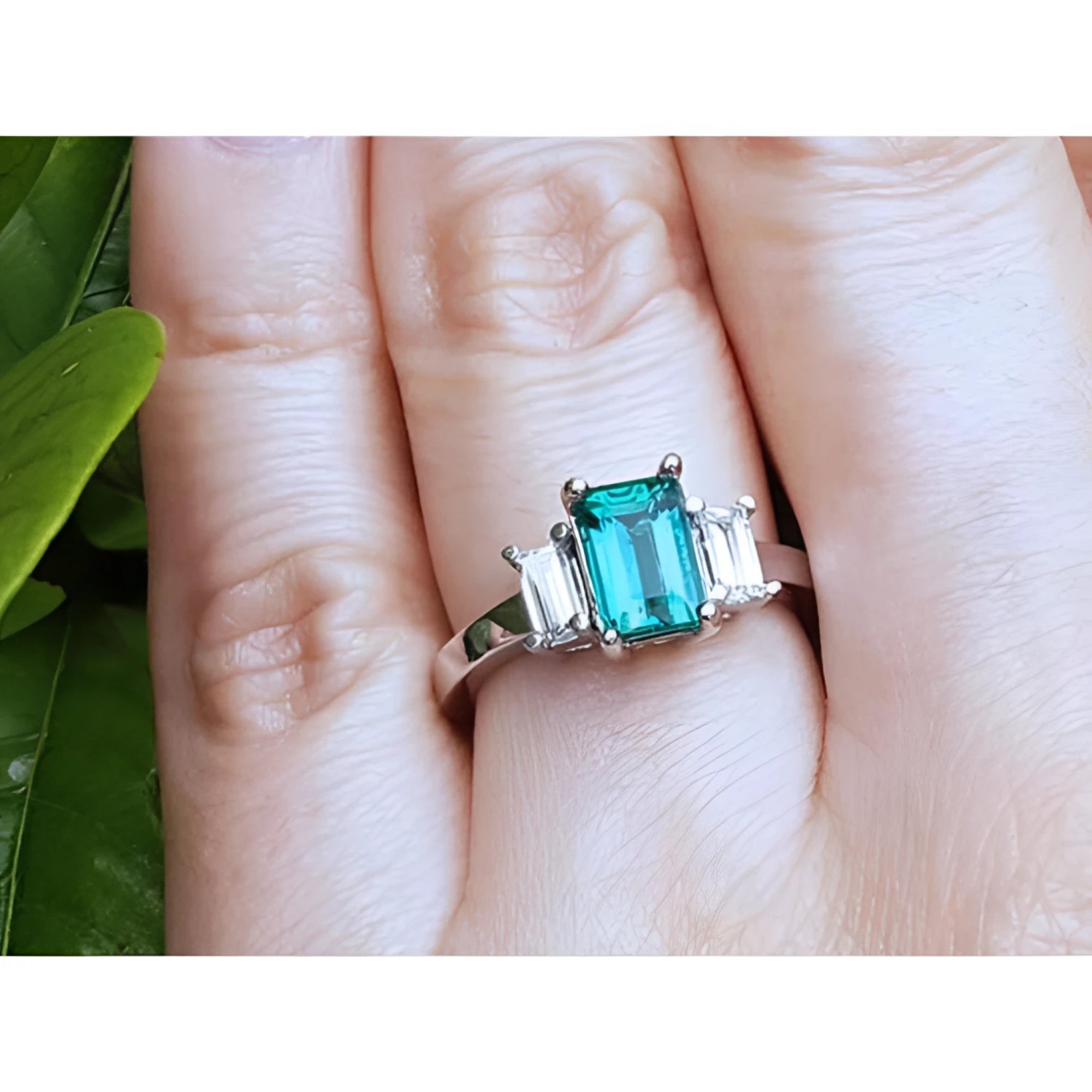 A three stone emerald and side straight baguettes diamond ring crafted in 18k white gold.
