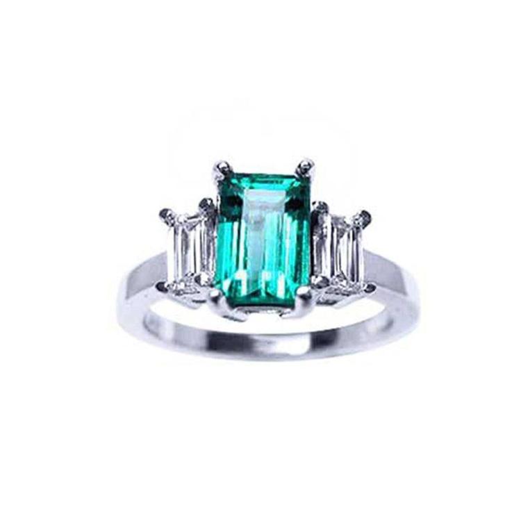 A colombian emerald three stone ring with side baguette natural diamonds, crafted in 18 white gold.