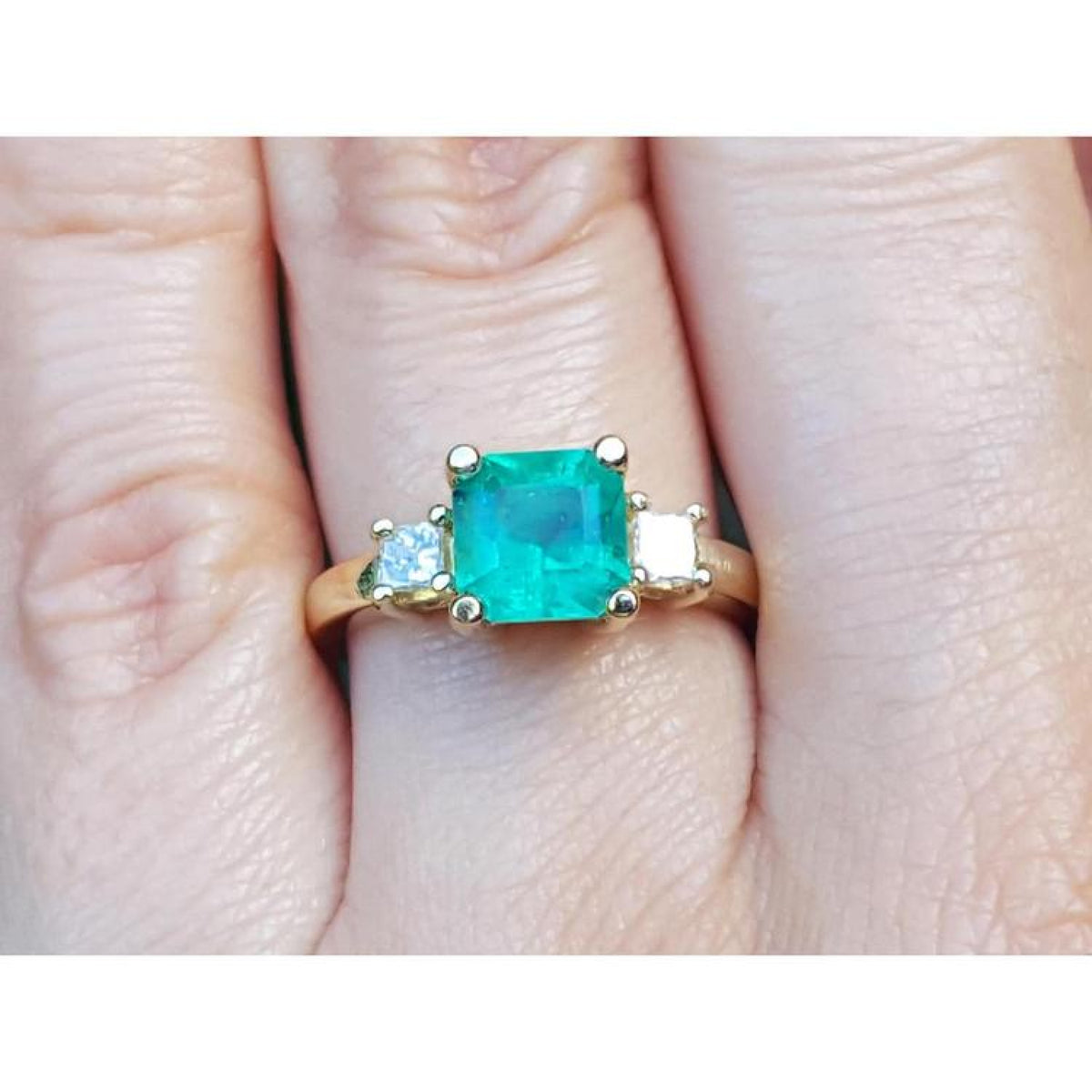 18K yellow gold three-stone ring with a square Colombian emerald and princess-cut side diamonds.