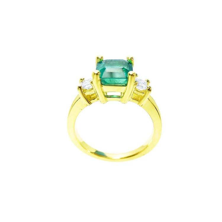 18K yellow gold three-stone ring with a square emerald and princess-cut side diamonds.