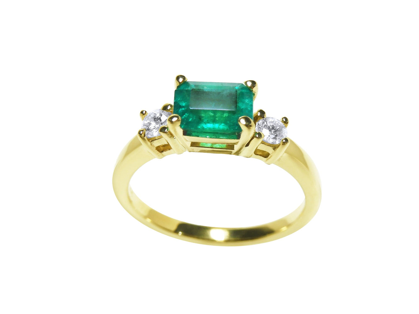 A yellow gold emerald ring east west design with side natural diamonds.