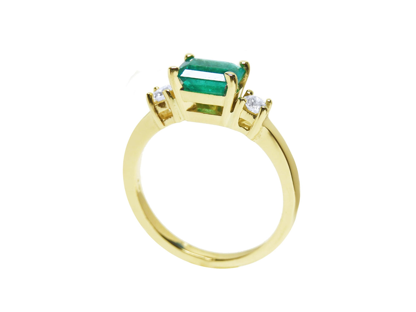 A detailed view of an emerald ring highlighting the top, side gallery, and band.
