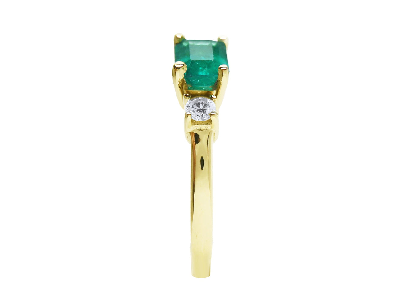 The side profile view of this three stone emerald ring displays the top and the band design.