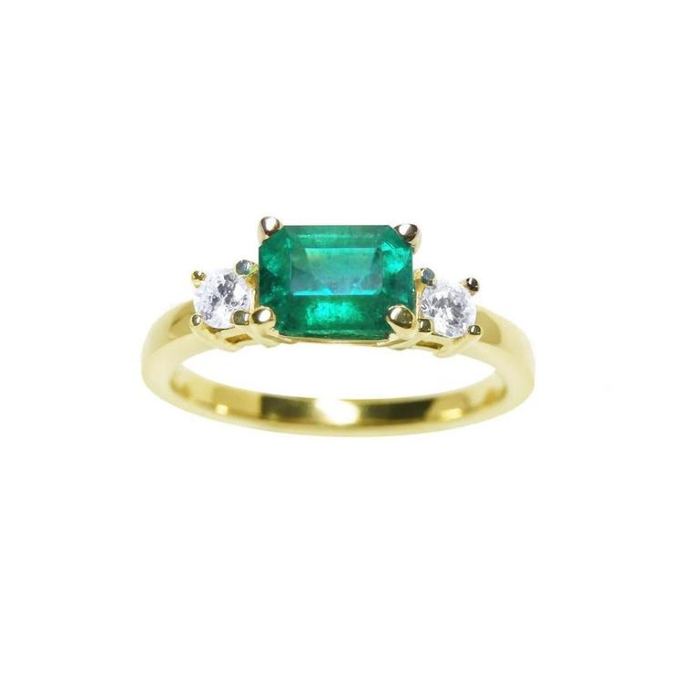 This three stone natural colombian emerald ring displays the main stone with side natural diamonds.