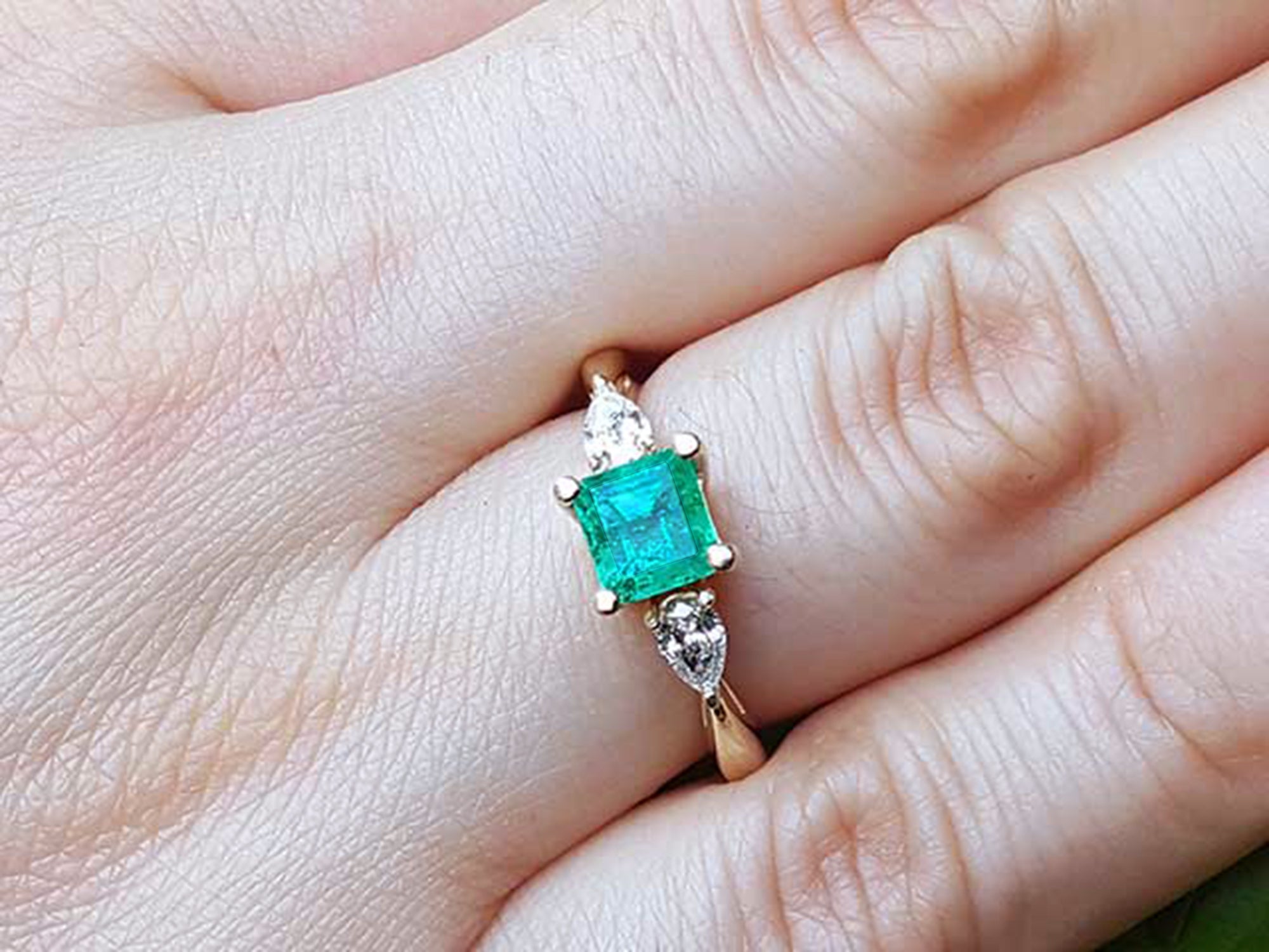 Emerald and diamond ring on a hand