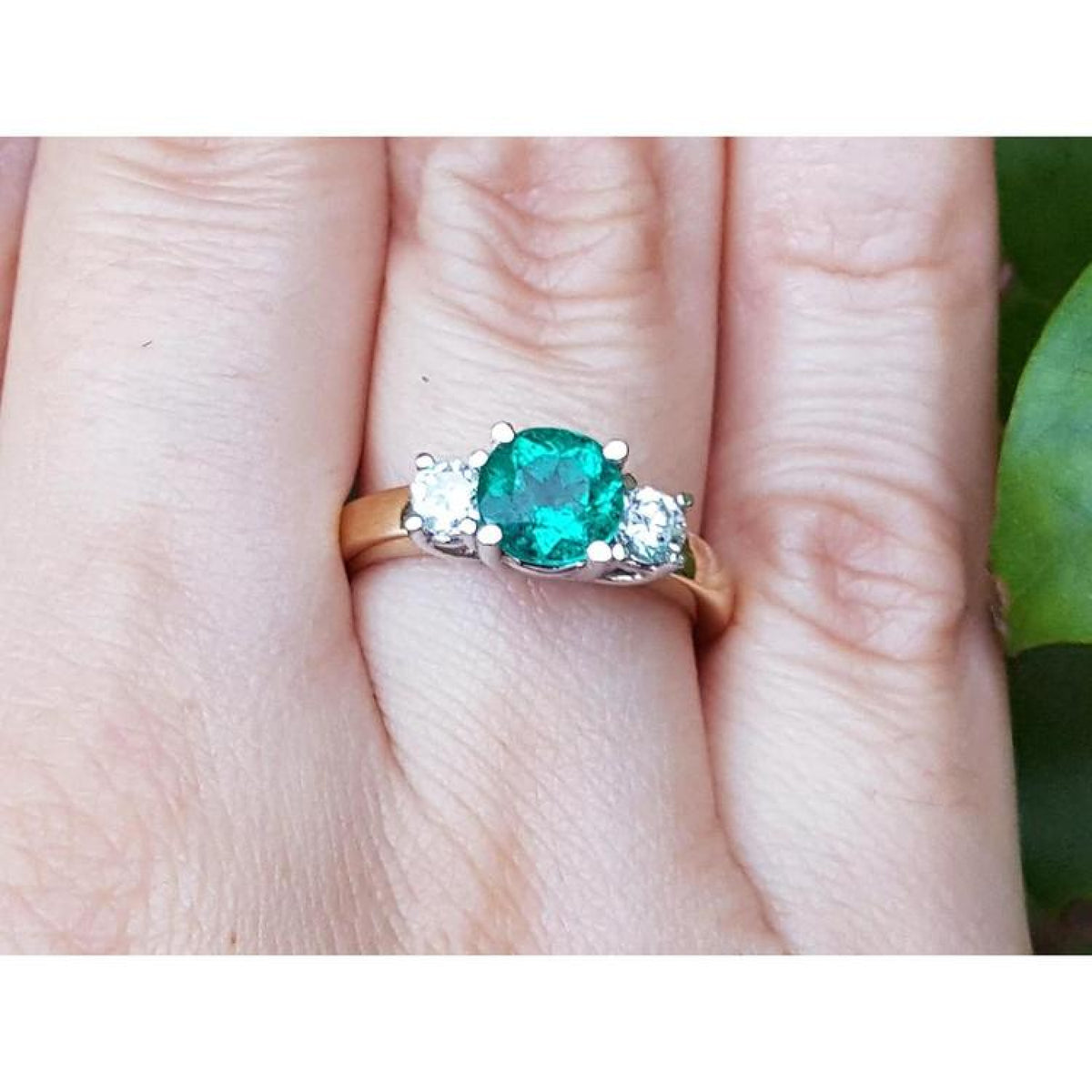 1.12 ct. round cut three stone emerald and diamond ring in 14k white and yellow gold.