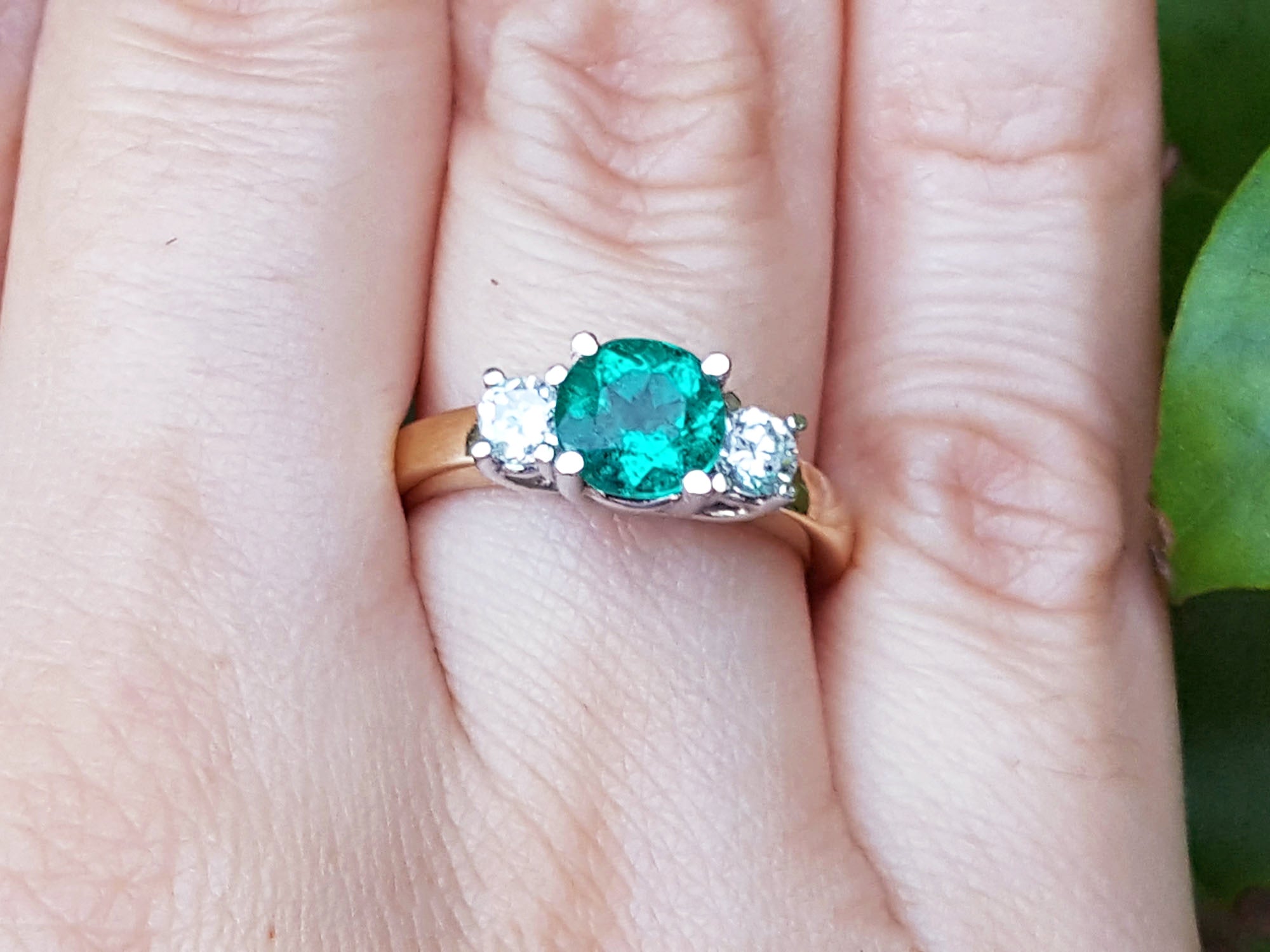 Bridal&#39;s May birthstone ring three stone round cut on a finger.