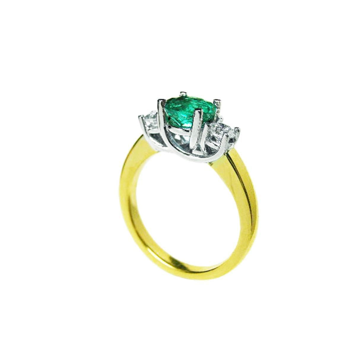 A 14k yellow gold emerald three stone ring and diamond accents on a white background.