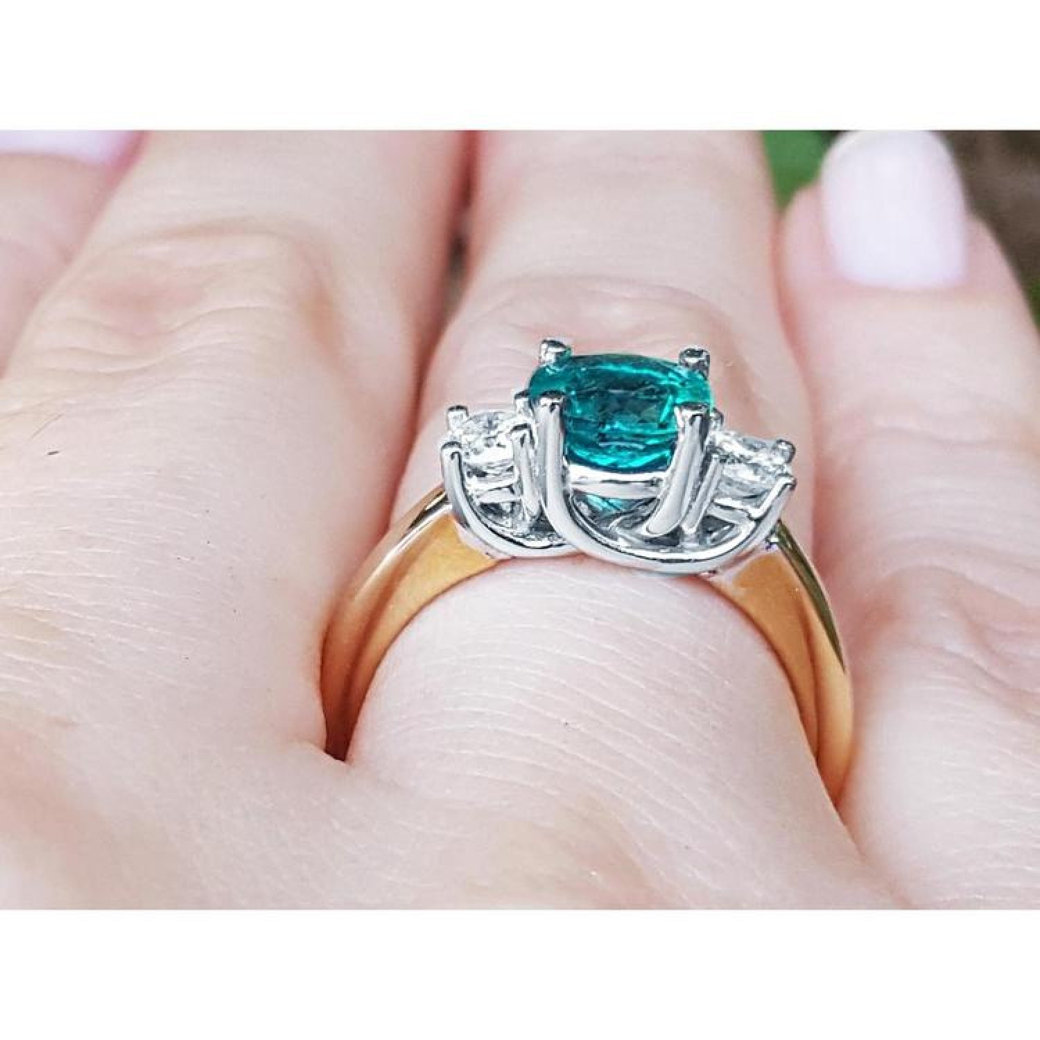 1.12 ct round cut bluish-green emerald three-stone ring with side diamonds in 14k white and yellow gold.