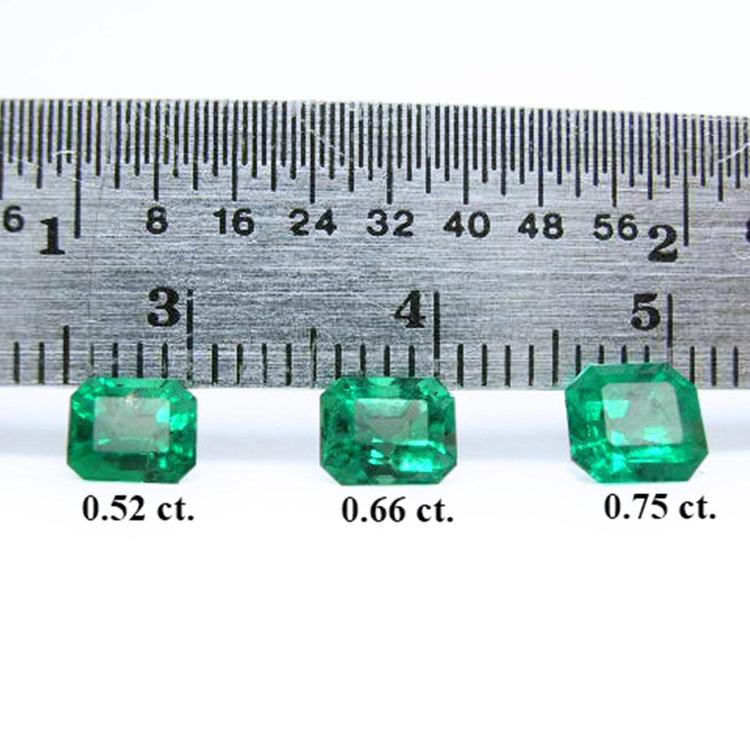 Three emerald-cut natural green emeralds, 0.52, 0.66, and 0.75 carat, displayed with a ruler.