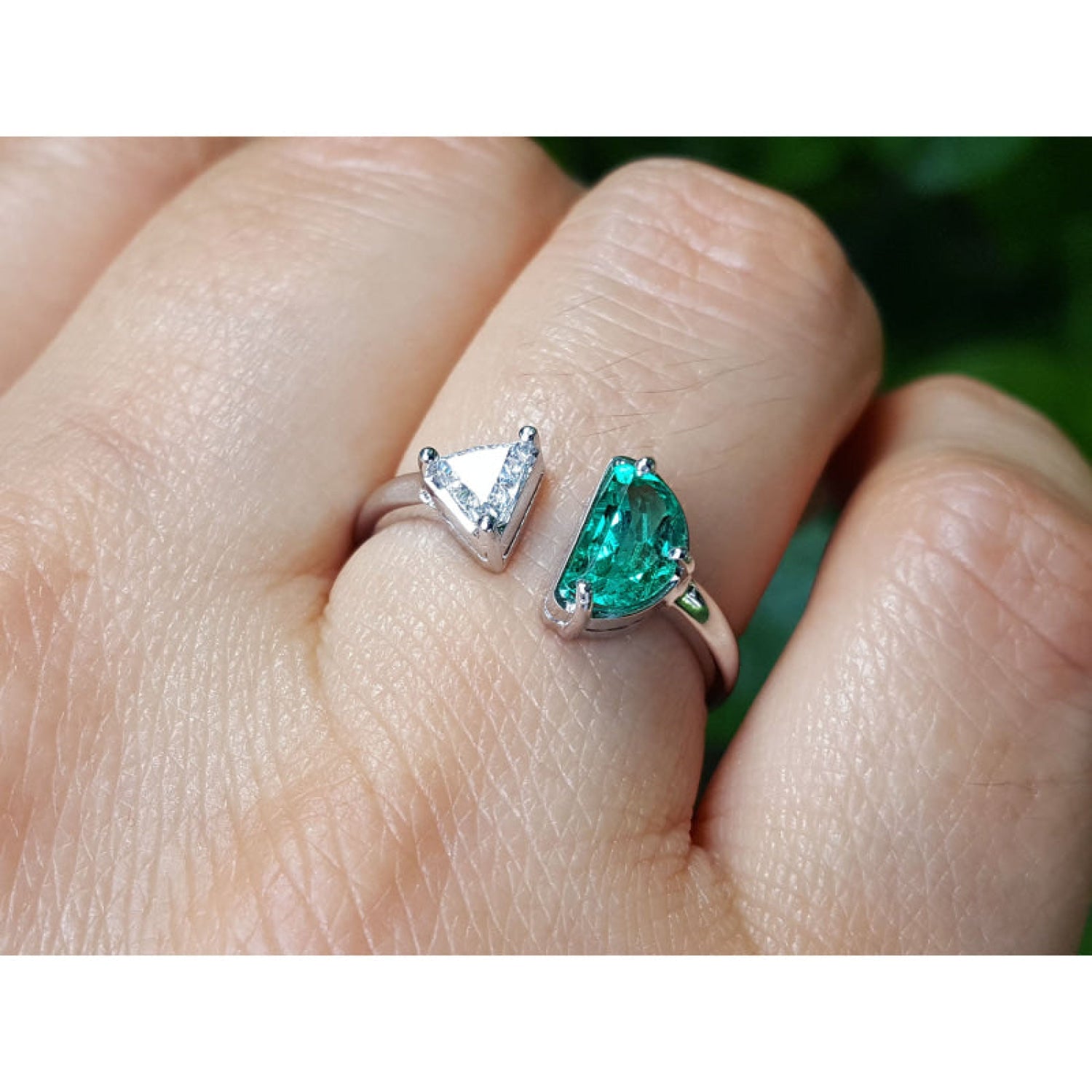 This women's negative space Toi et Moi ring features a natural Colombian emerald and a trillion-cut diamond, handcrafted in 18k solid white gold.