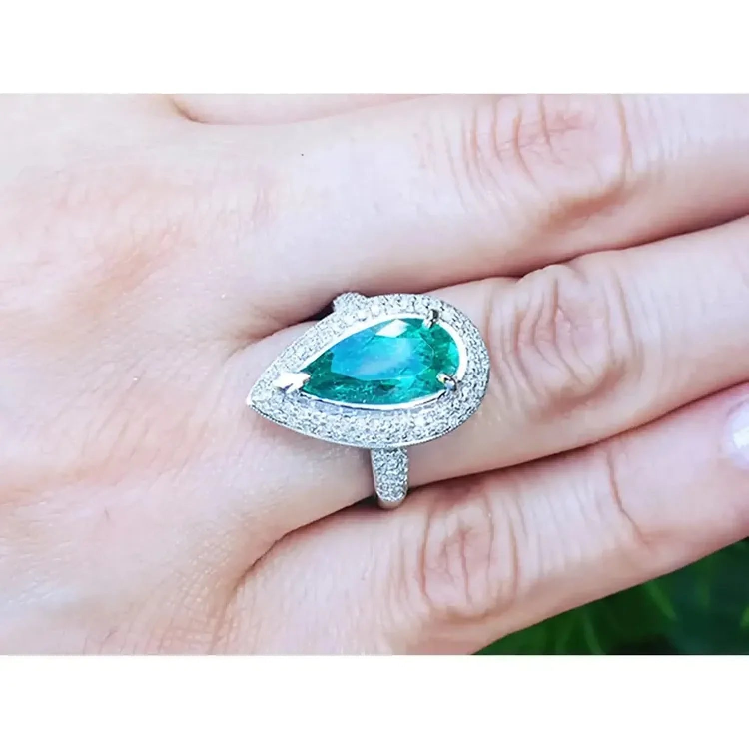 Anillo de oro blanco 14k con esmeralda colombiana corte pera 3.35 ct y halo de diamantes.
