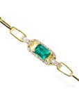 Gold paperclip bracelet with a square emerald on a topside position view.