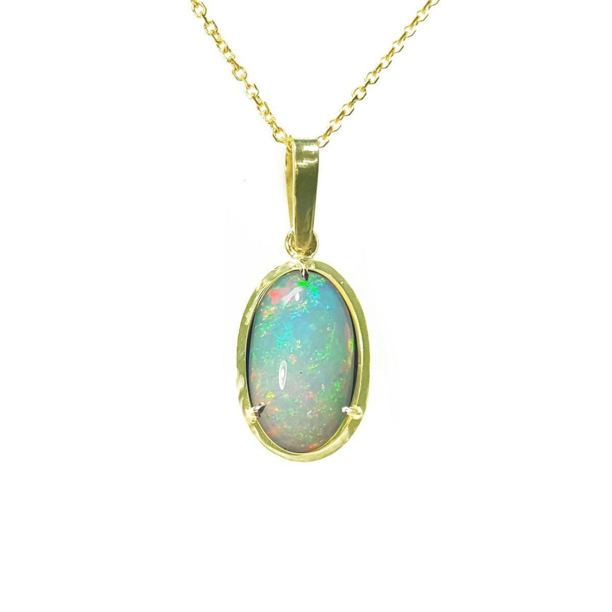 Opal pendant on a gold chain on a topside position view against a white background.