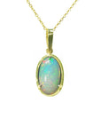 Opal pendant on a gold chain on a topside position view against a white background.