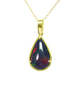 Teardrop-shaped black opal pendant on a gold chain on topside view against a white background.
