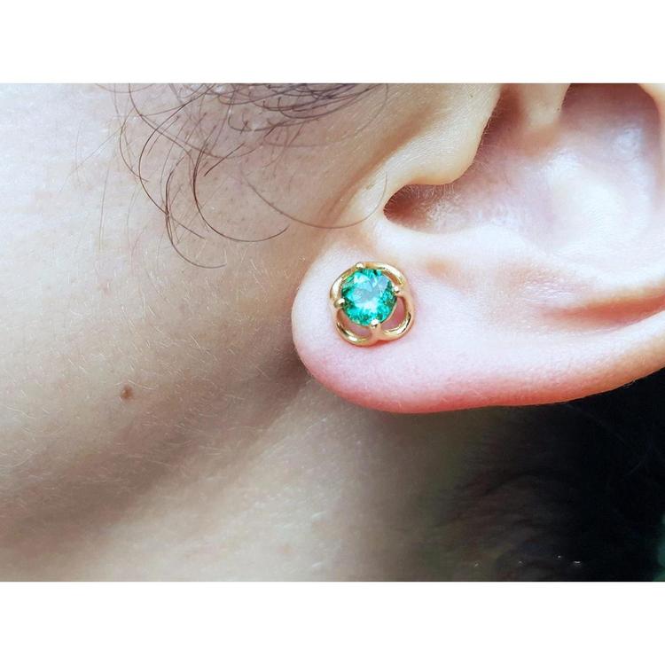 Close-up of an ear wearing a tulip natural emerald stud earring.