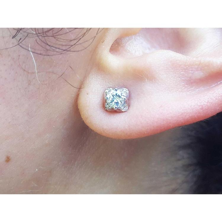 A woman's ear wearing a 14k white gold diamond stud earring, tulip style.