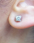 A woman's ear wearing a white gold diamond stud earring, tulip style.