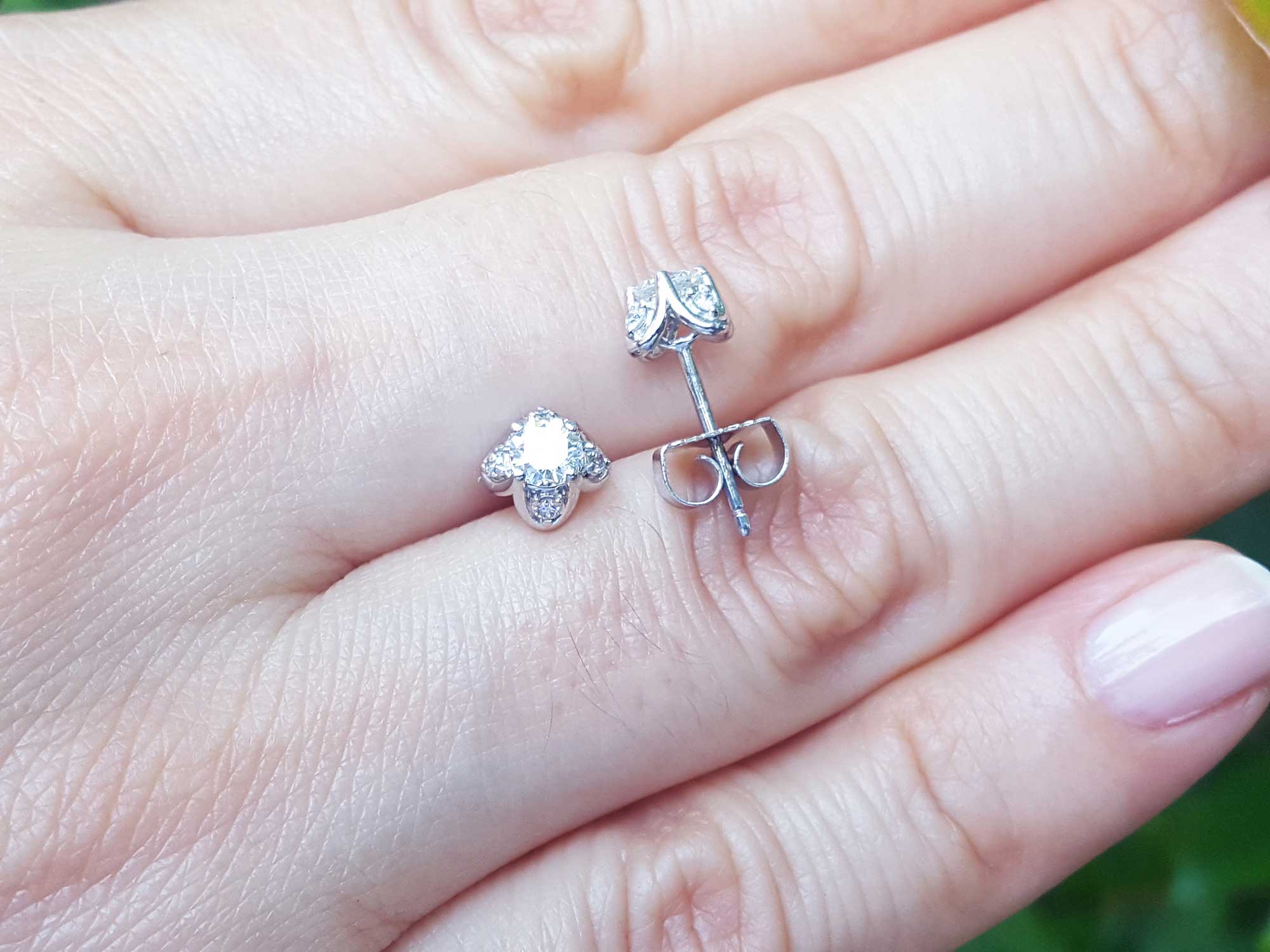 On hand displaying a natural diamond tulip stud earrings in white gold.