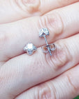 On hand displaying a natural diamond tulip stud earrings in white gold.